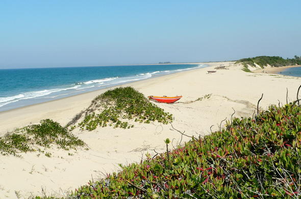 A lone fishing boat on the dunes of a deserted beach.